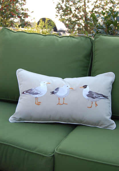 Seagull Flash Mob Lumbar Pillow styled on a green outdoor sofa.