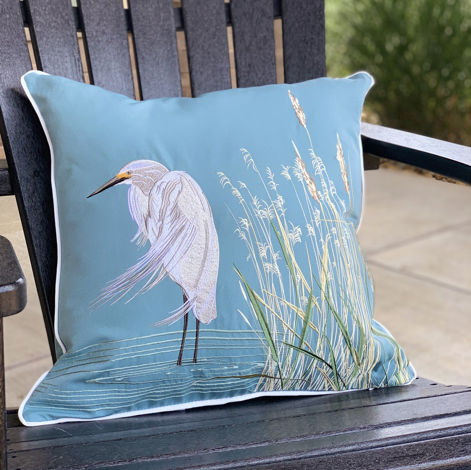 Snowy White Egret Indoor Outdoor Pillow styled on an Adirondack chair.