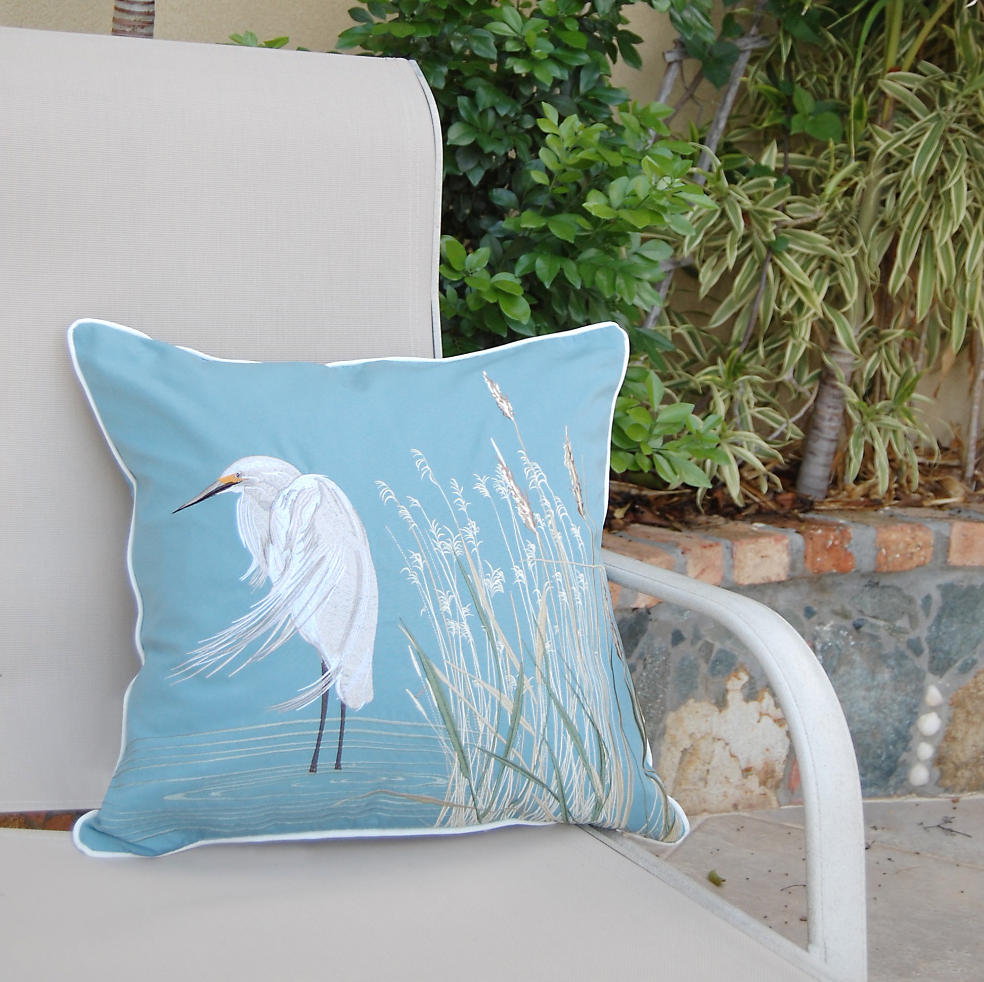 Snowy White Egret Indoor Outdoor Pillow styled on a patio chair.