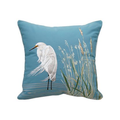 An embroidered white egret standing in a marshy water & cattails on a blue background.