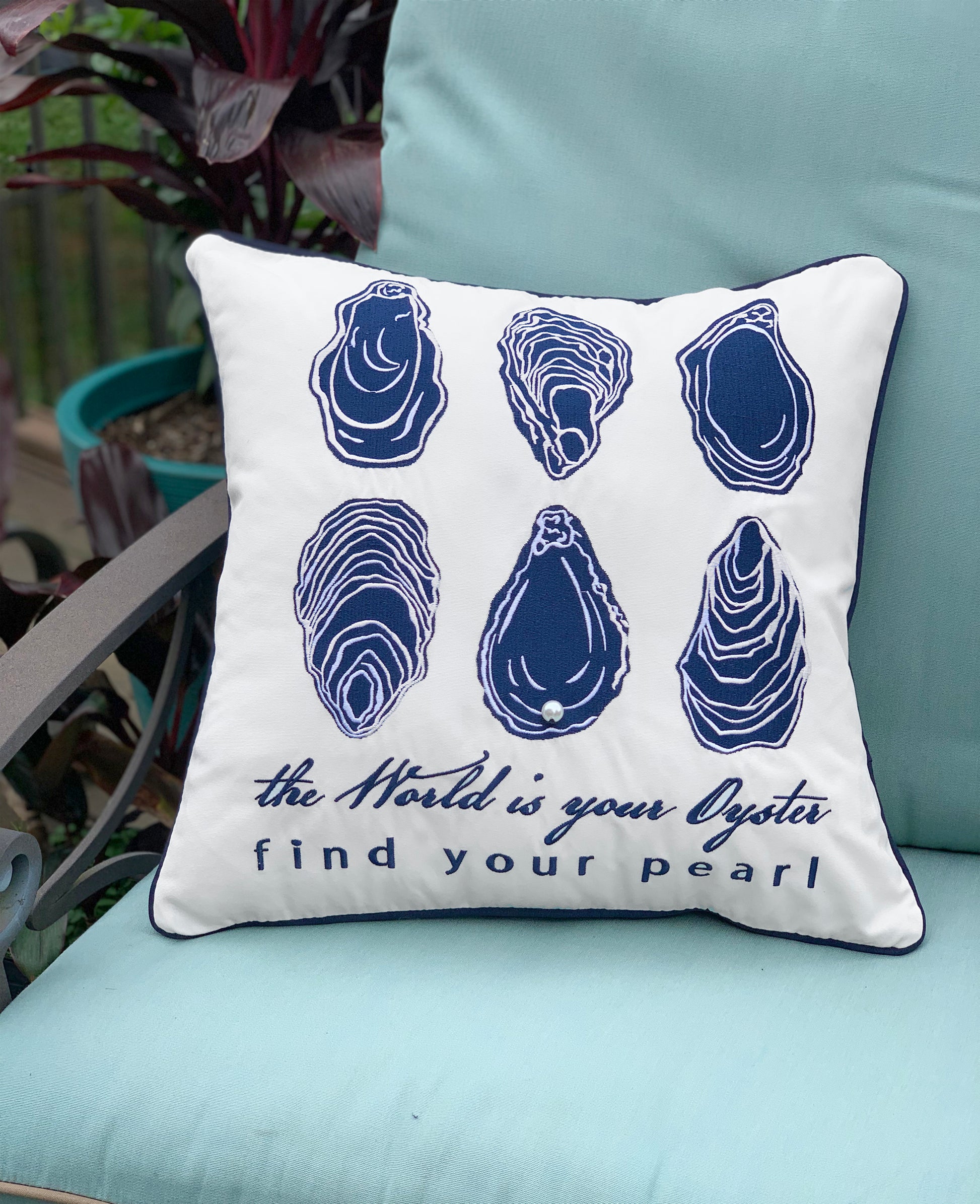 The World Is Your Oyster Indoor Outdoor Pillow is styled on a patio chair.