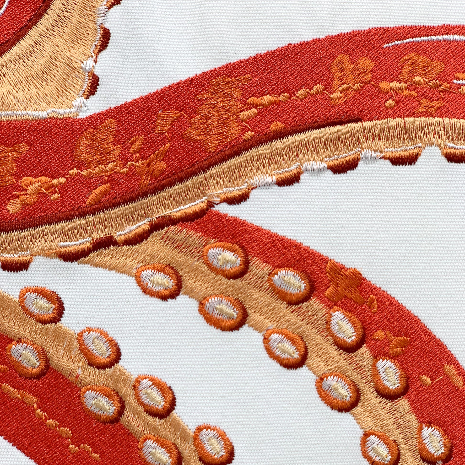 Detail shot of the Tropical Punch Coral Octopus pillow's embroidery work.