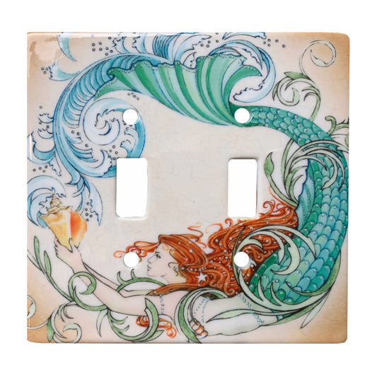 ceramic double toggle switch plate featuring illustrative graphic of a mermaid with a green tail holding a conch shell.