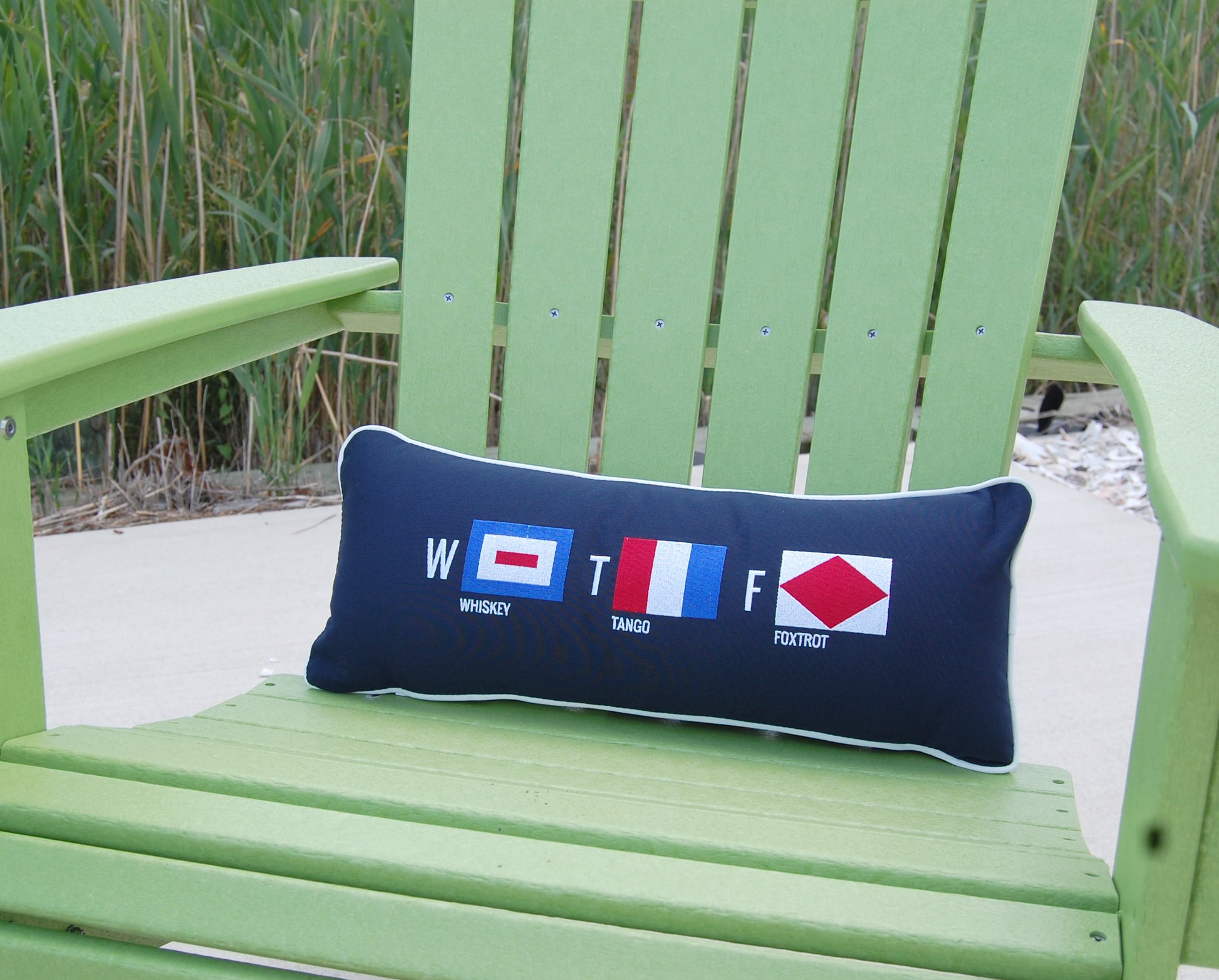 Whiskey Tango Foxtrot outdoor pillow styled on a green Adirondack chair.