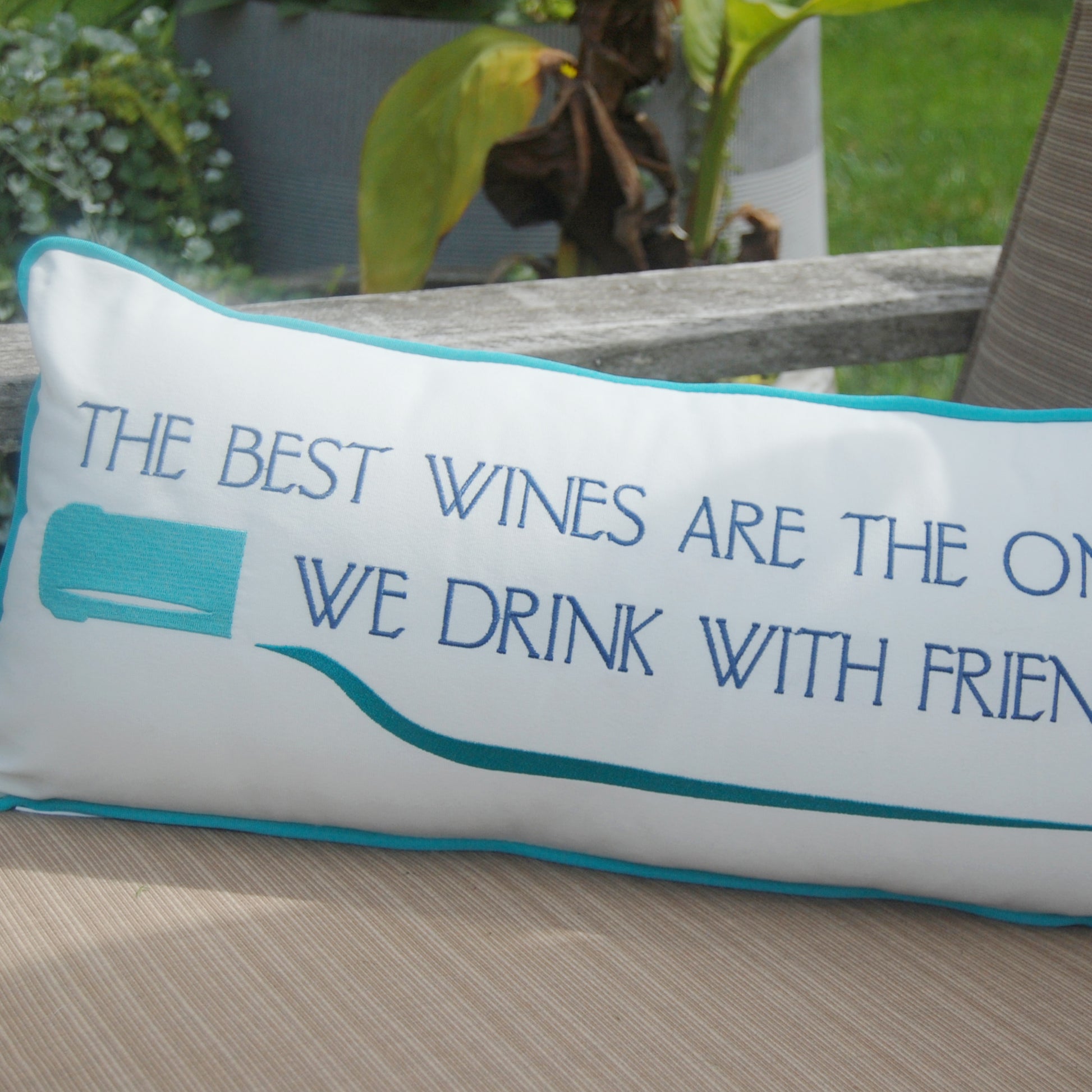 Wine Friends Lumbar Indoor Outdoor Pillow styled on a patio chair.
