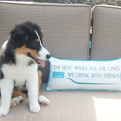 Wine Friends Lumbar Indoor Outdoor Pillow styled on a patio chair with a puppy.