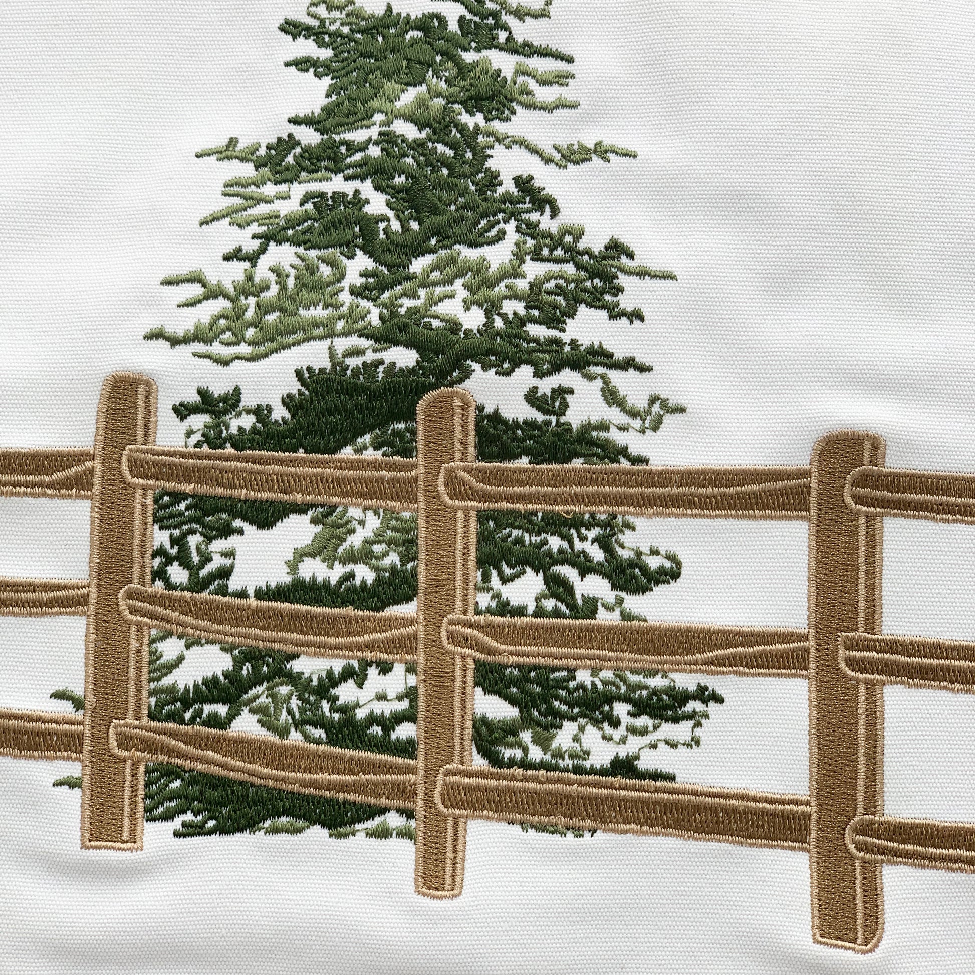 Detail shot of the fence & everygreens on the Winter Chill Neutral Indoor Outdoor pillow.