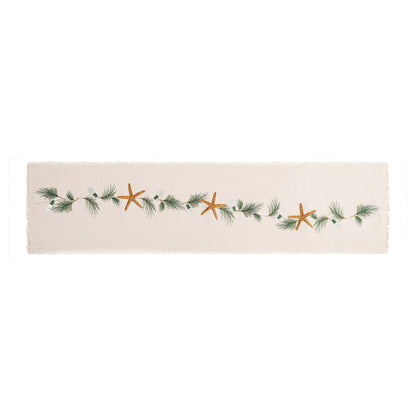 Natural cotton fringed table runner featuring an embroidered sea star, holiday lights, and evergreen needles.