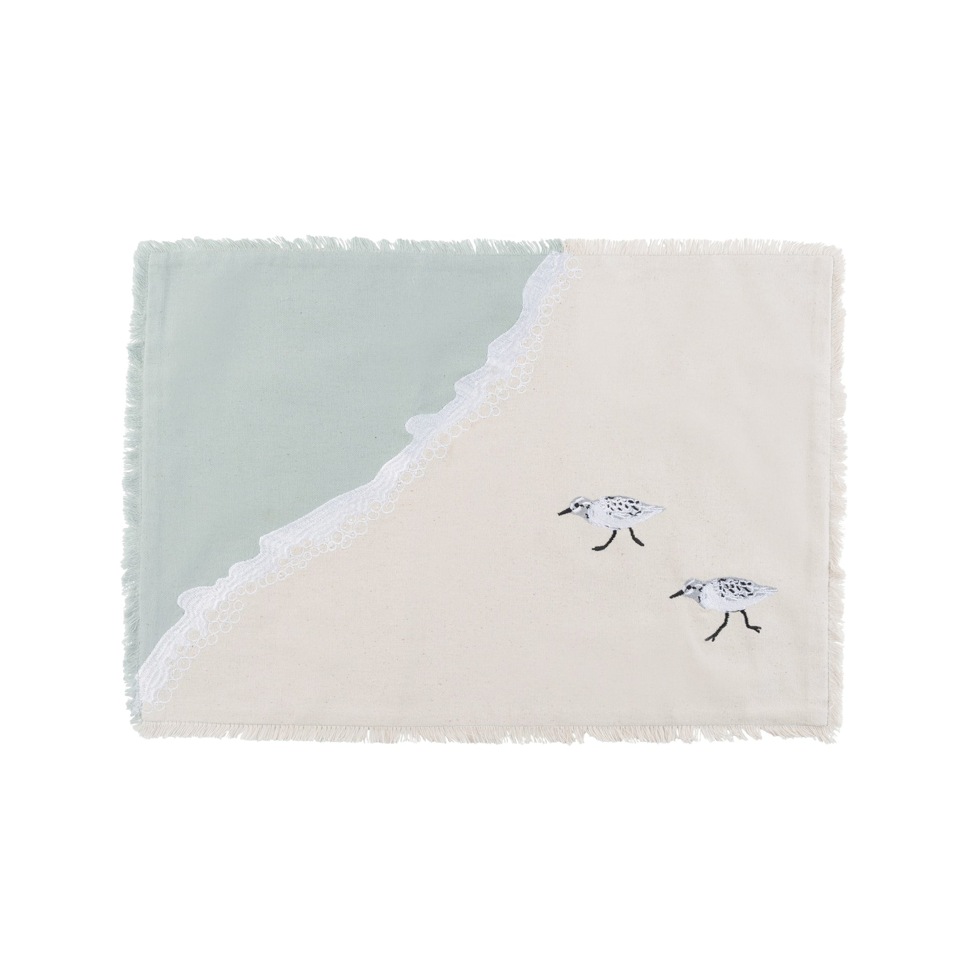 Sandpipers embroidered on a cotton fringed placemat featuring blue waves on sand. 